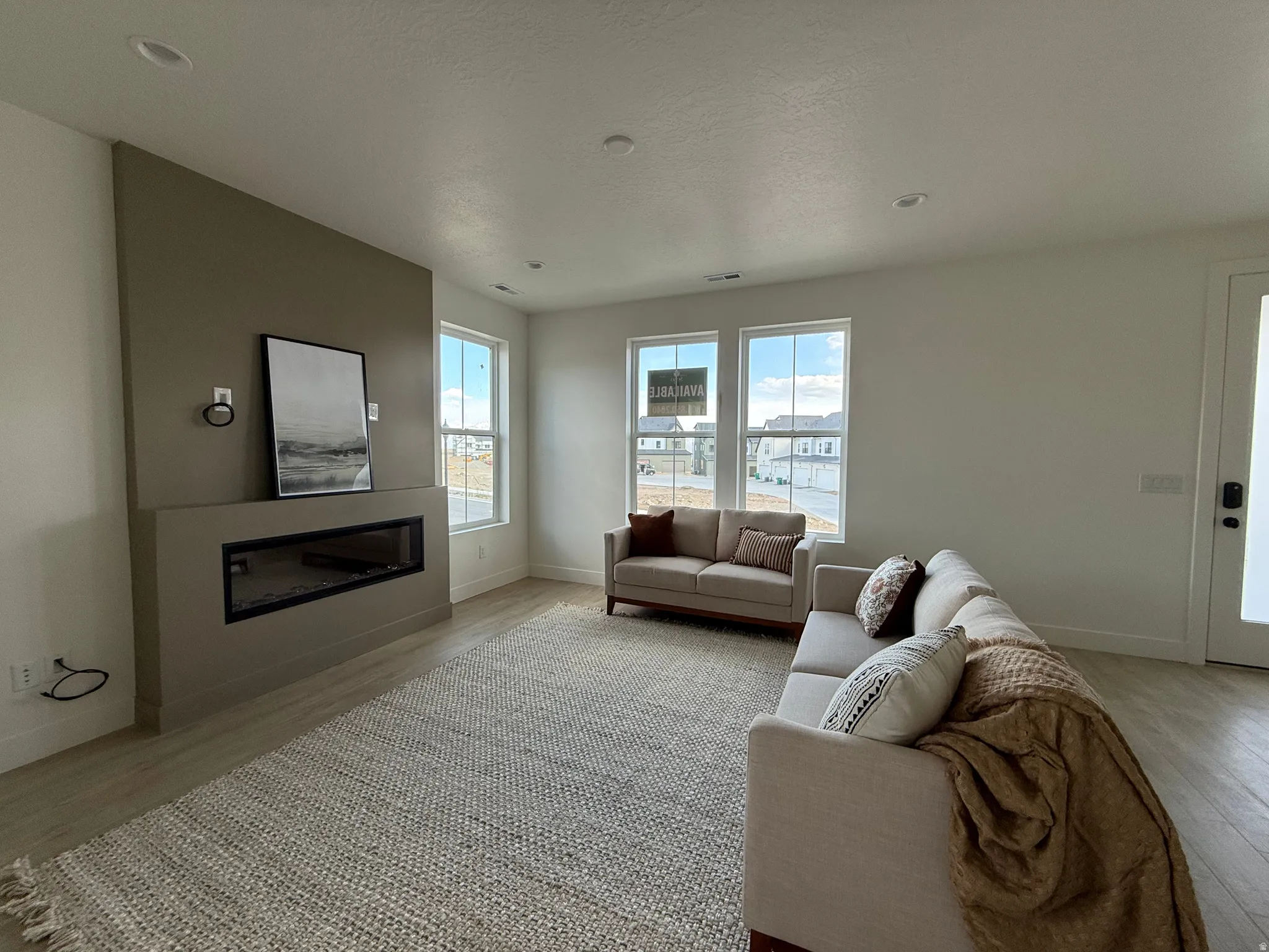 Living room featuring a glass covered fireplace and light wood-style floors