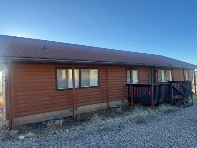 Back of property featuring crawl space, a deck, roof with shingles, and faux log siding