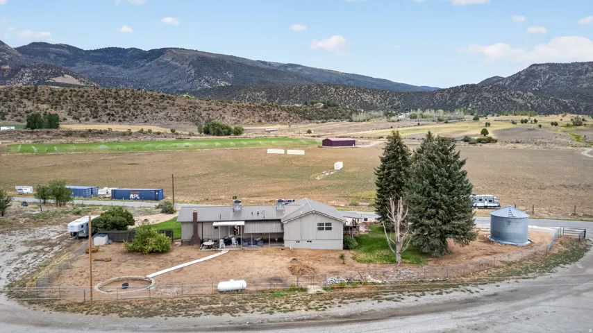 Expansive rural property featuring a main residence with a covered patio, a detached storage building, and an agricultural tank