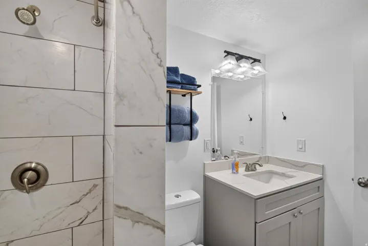 Unit 2A: Shower with brushed nickel fixtures and large format tile surround