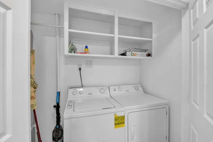 Unit 3: White shaker-style overhead cabinetry, laundry appliances, and a built-in hanging rod
