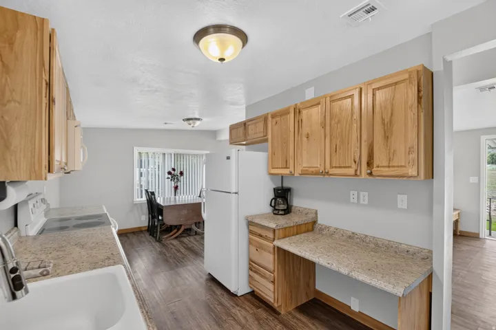 Unit 3: Laminate wood-finish flooring, light wood-finish cabinetry, speckled countertops, and an integrated white sink