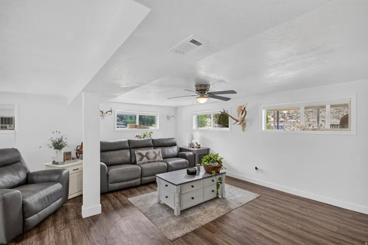 Unit 2B: Wood-finish flooring, white walls, multiple windows, and a ceiling fan with integrated lighting