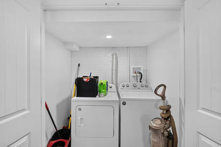Unit 2B: Dedicated laundry area with a white washer and dryer, featuring overhead recessed lighting and white painted walls