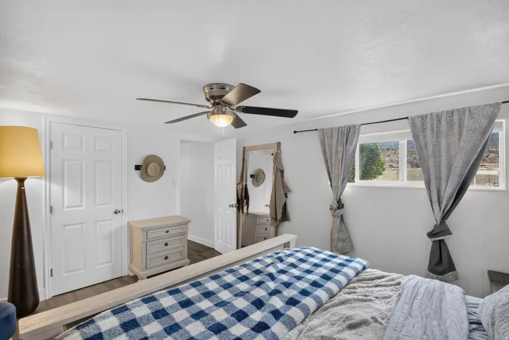 Unit 2B: White interior walls, two paneled doors, ceiling fan with integrated lighting, wood-finish flooring, and a multi-pane window