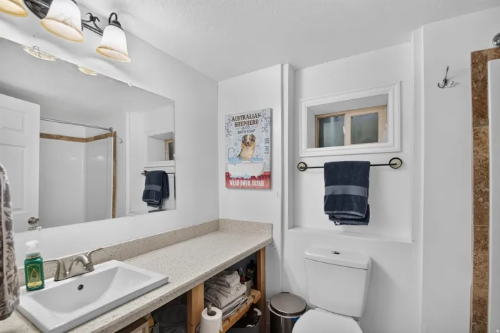 Unit 2B: White vanity with a light-toned countertop, a rectangular undermount sink, and a chrome faucet