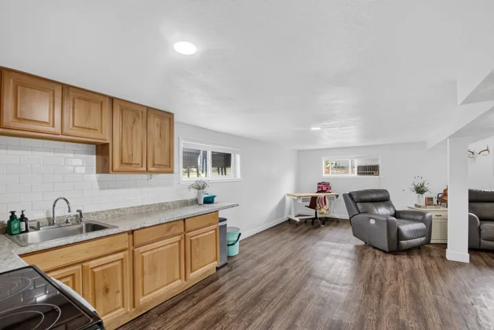 Unit 2B: Wood-finish flooring, recessed lighting, double-basin stainless steel sink, wood cabinetry, and a white subway tile backsplash
