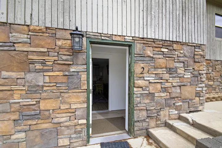 Stone veneer exterior with wood paneling, featuring a wall-mounted lantern light fixture