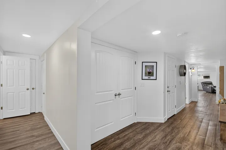Unit 2B: Wood-finish flooring throughout, bright white walls, recessed ceiling lighting, and multiple white paneled doors