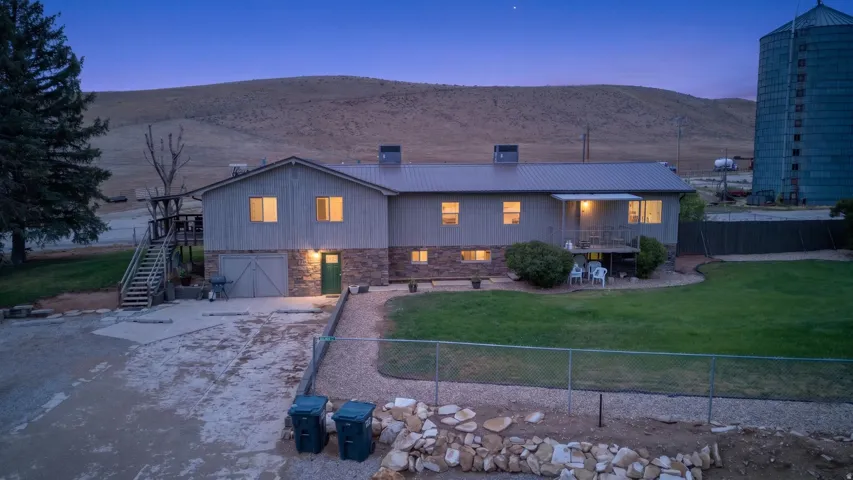 Two-story exterior with a metal roof, stone-clad lower level, and a covered balcony