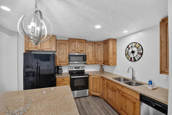 Unit 1: Kitchen featuring wood cabinetry, stainless steel appliances, dual basin sink, recessed lighting, and a pendant light fixture