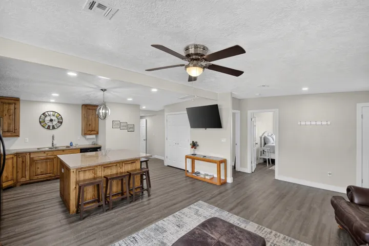 Unit 1: Kitchen island with granite-style countertop, wood-finish cabinetry, and stainless steel sink
