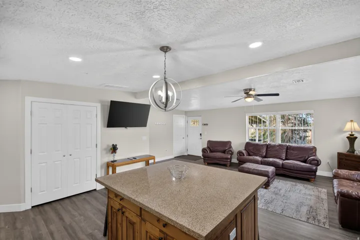 Unit 1: Kitchen island with a granite-style countertop, wood-finish flooring, recessed lighting, and a ceiling fan