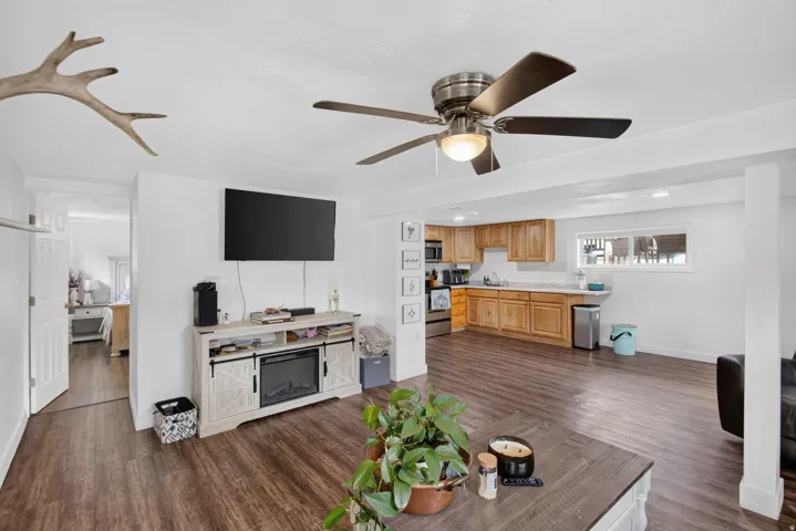 Unit 2B: Open-concept living space featuring wood-finish flooring, a ceiling fan, and a built-in media console with an electric fireplace
