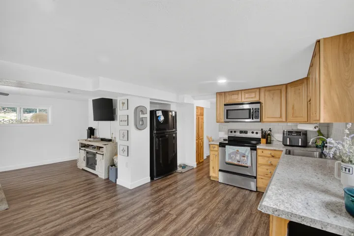 Unit 2B: Kitchen area featuring wood-finish flooring, light-toned cabinetry, stainless steel appliances, and a light-toned countertop