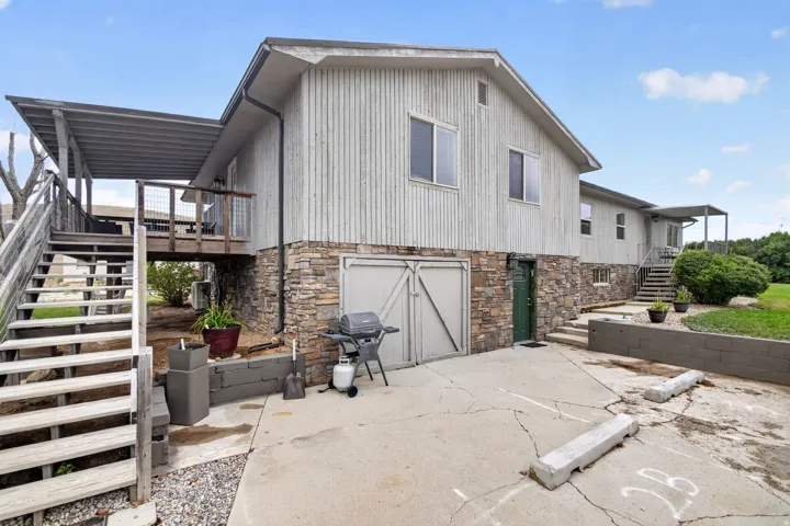 Stone veneer foundation, wood siding exterior, covered porch, exterior wood staircase, and concrete drive