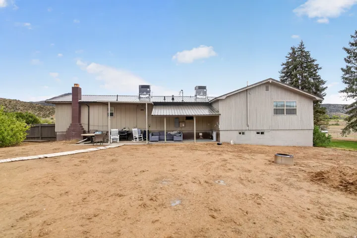 Rear exterior featuring a covered patio, metal roof, and a brick chimney