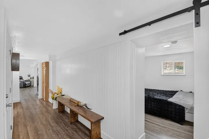 Unit 2B: Wood-finish flooring, white vertical paneled wall, recessed lighting, and a black barn door track