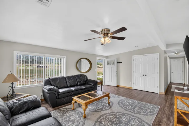 Unit 3: Spacious living area featuring wood-finish flooring, a ceiling fan with integrated lighting, and a sliding glass door