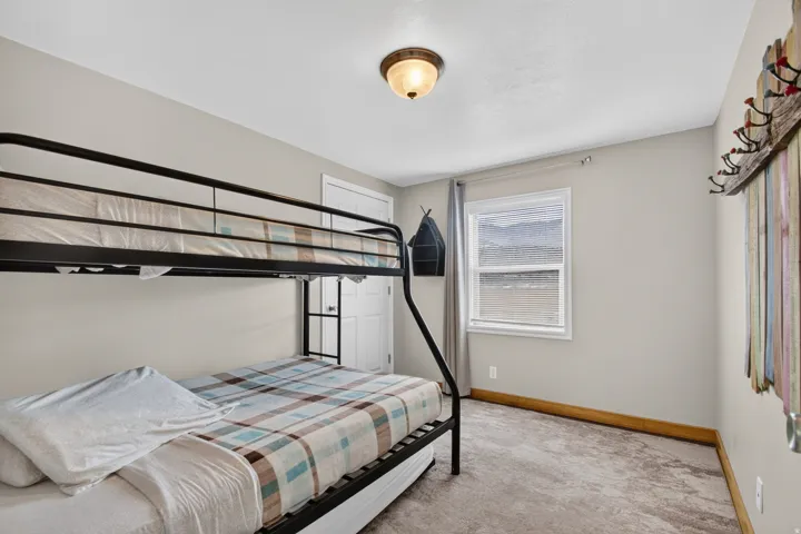 Unit 3: Neutral wall paint, window with vertical blinds, textured carpet, white trim, and a semi-flush mount light fixture