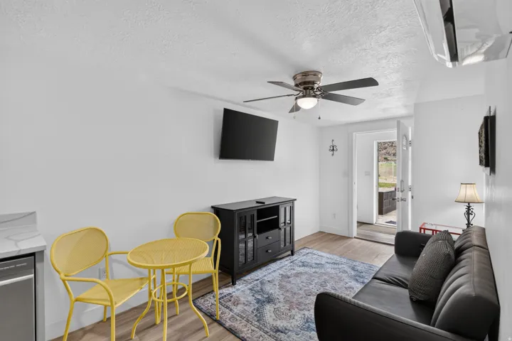 Unit 2A: Wood-finish flooring, ceiling fan, white walls, and a wall-mounted air conditioning unit