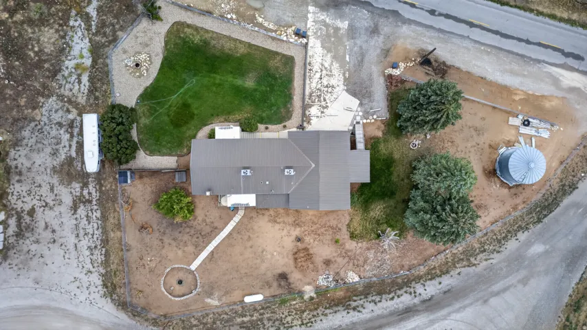 Property featuring a dark-toned roof, a circular stone-edged fire pit, a silo structure, and mature trees