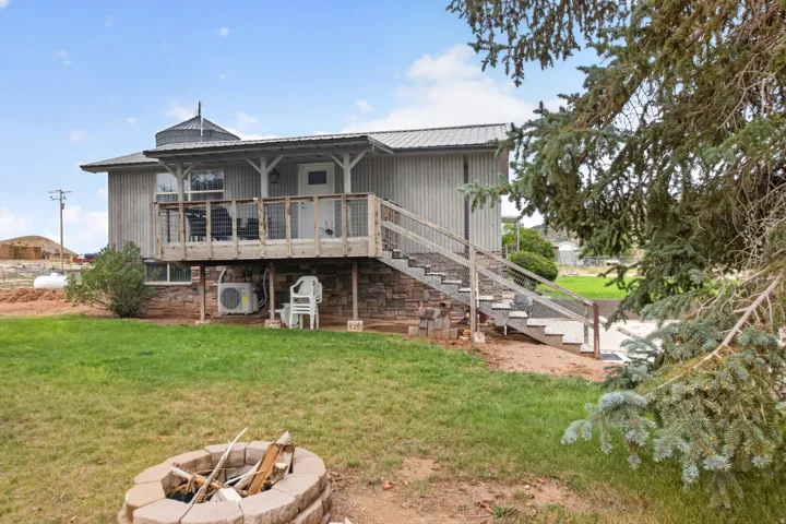 Elevated exterior featuring a covered porch, stone foundation, metal roof, and an exterior staircase