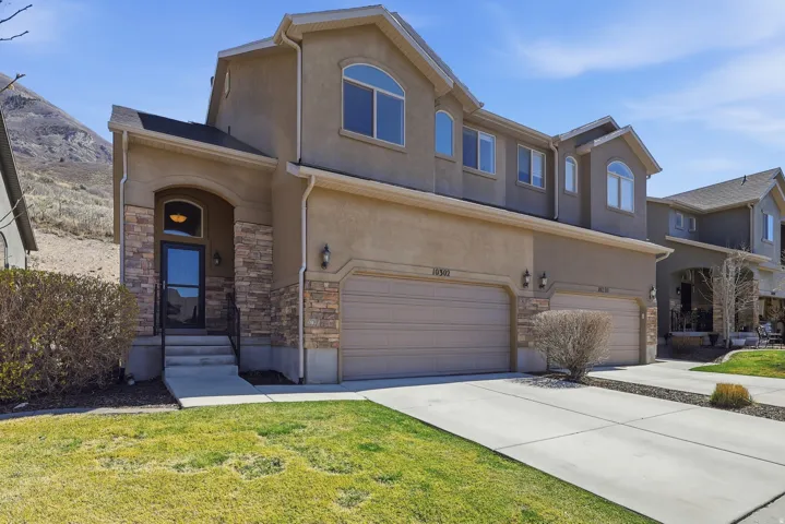 View of front of property with stucco siding, stone siding, and driveway