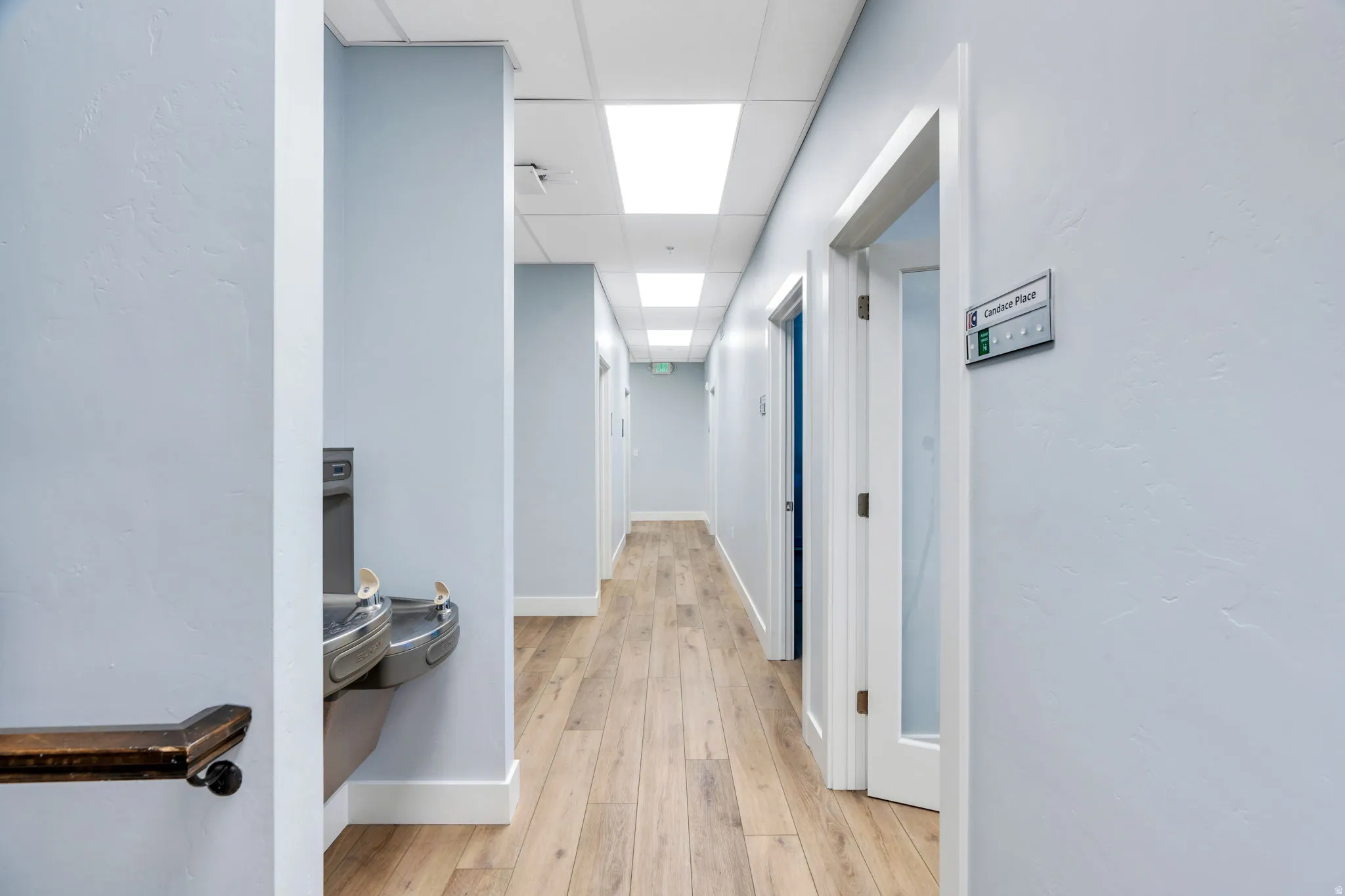 Hall with a paneled ceiling and light wood-type flooring