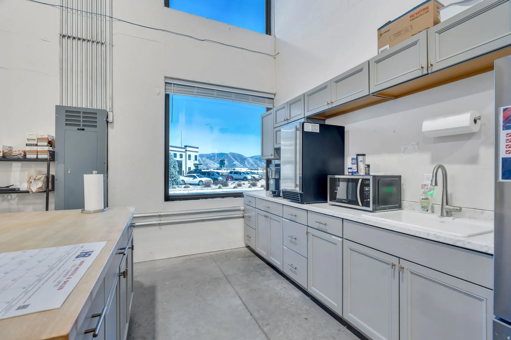 Kitchen with gray cabinets, unfinished concrete flooring, and stainless steel appliances