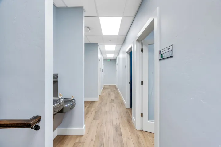 Hall with a paneled ceiling and light wood-type flooring