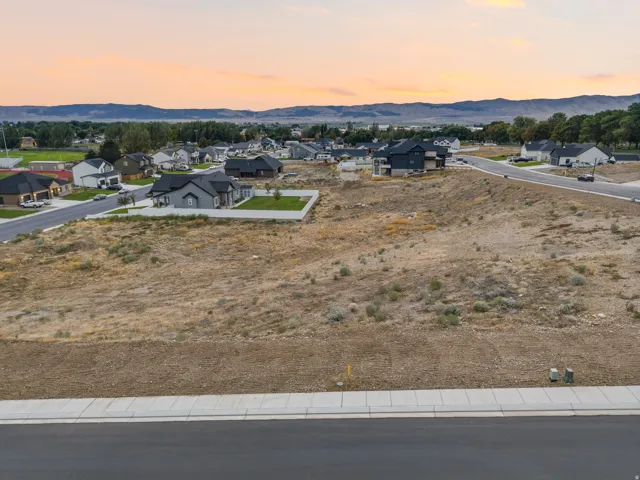 Expansive vacant lot with a paved street, concrete sidewalk, and utilities installed