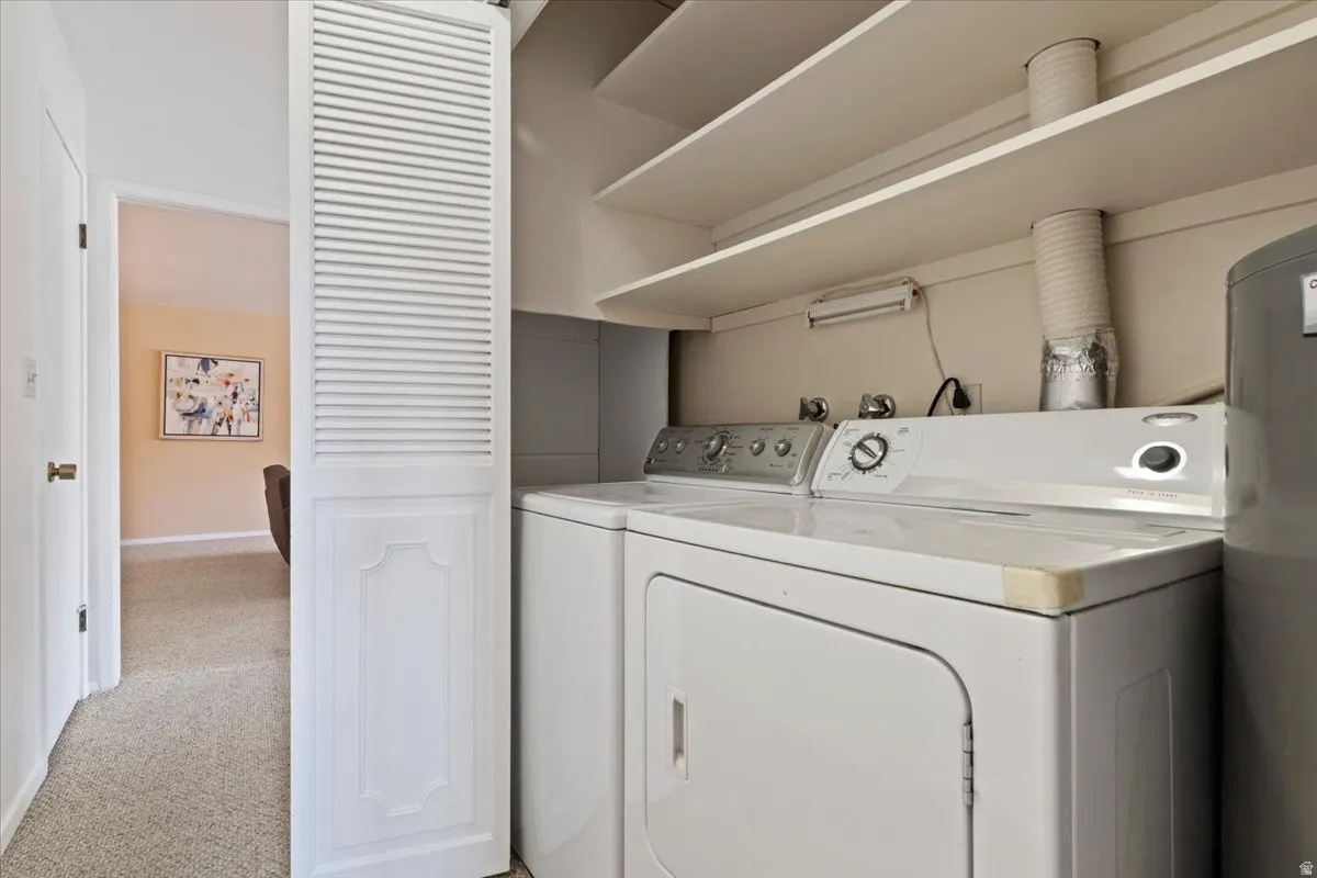 Laundry area with light carpet, washing machine and dryer, and water heater