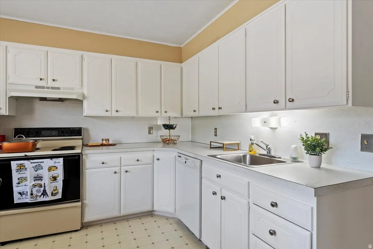 Kitchen featuring light flooring, white appliances, white cabinetry, light countertops, and crown molding