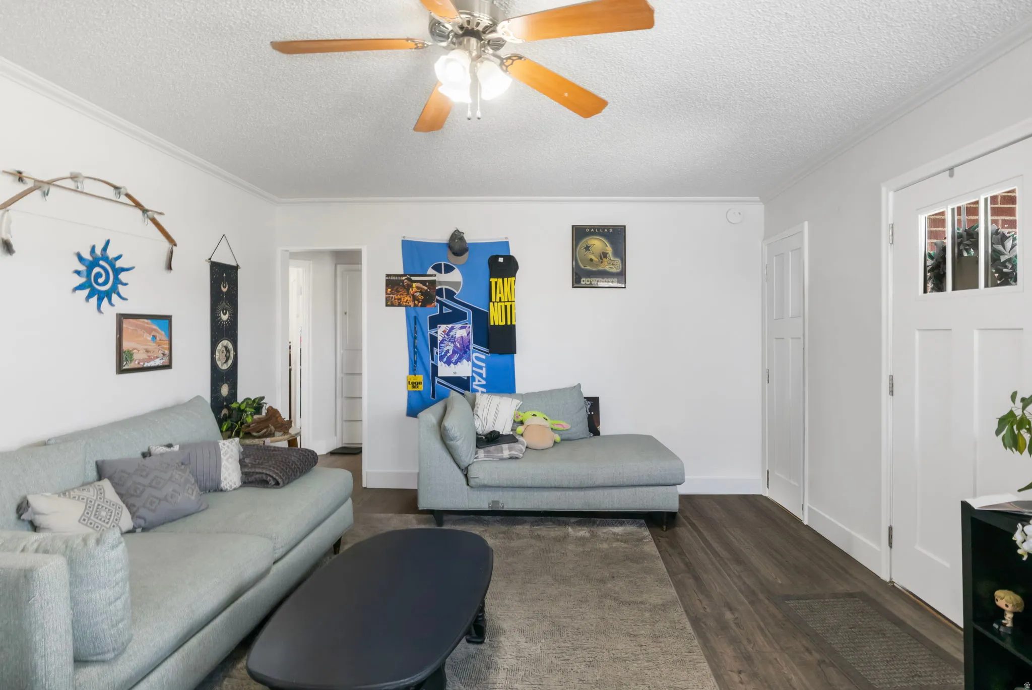 Living room featuring a textured ceiling, dark wood finished floors, and a ceiling fan