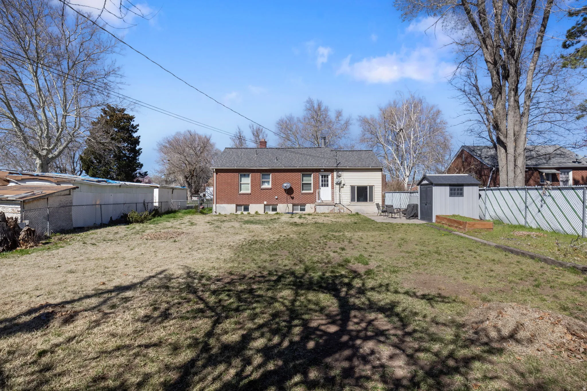 Rear view of house featuring a storage shed, a fenced backyard, a patio area, and a chimney