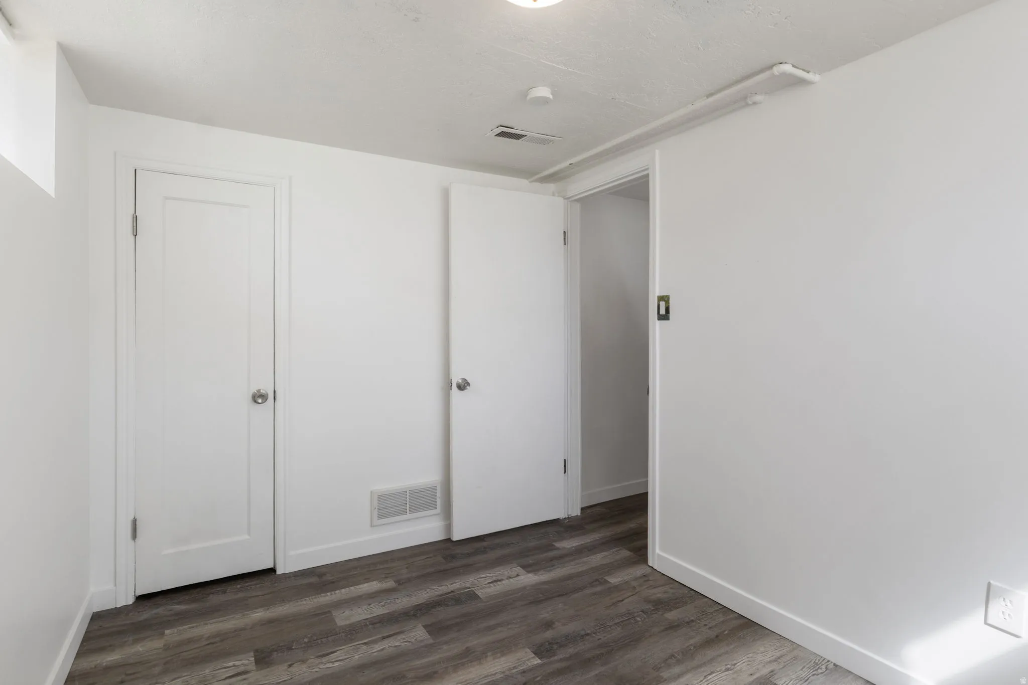 Bedroom 2 with dark vinyl flooring and baseboards