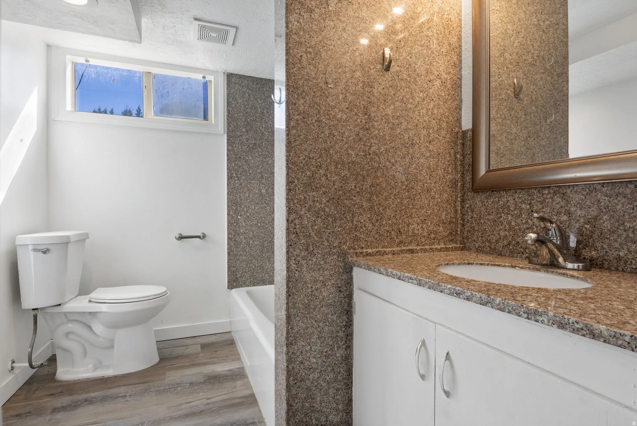 Bathroom with vanity, light vinyl floors, and shower / bath combination