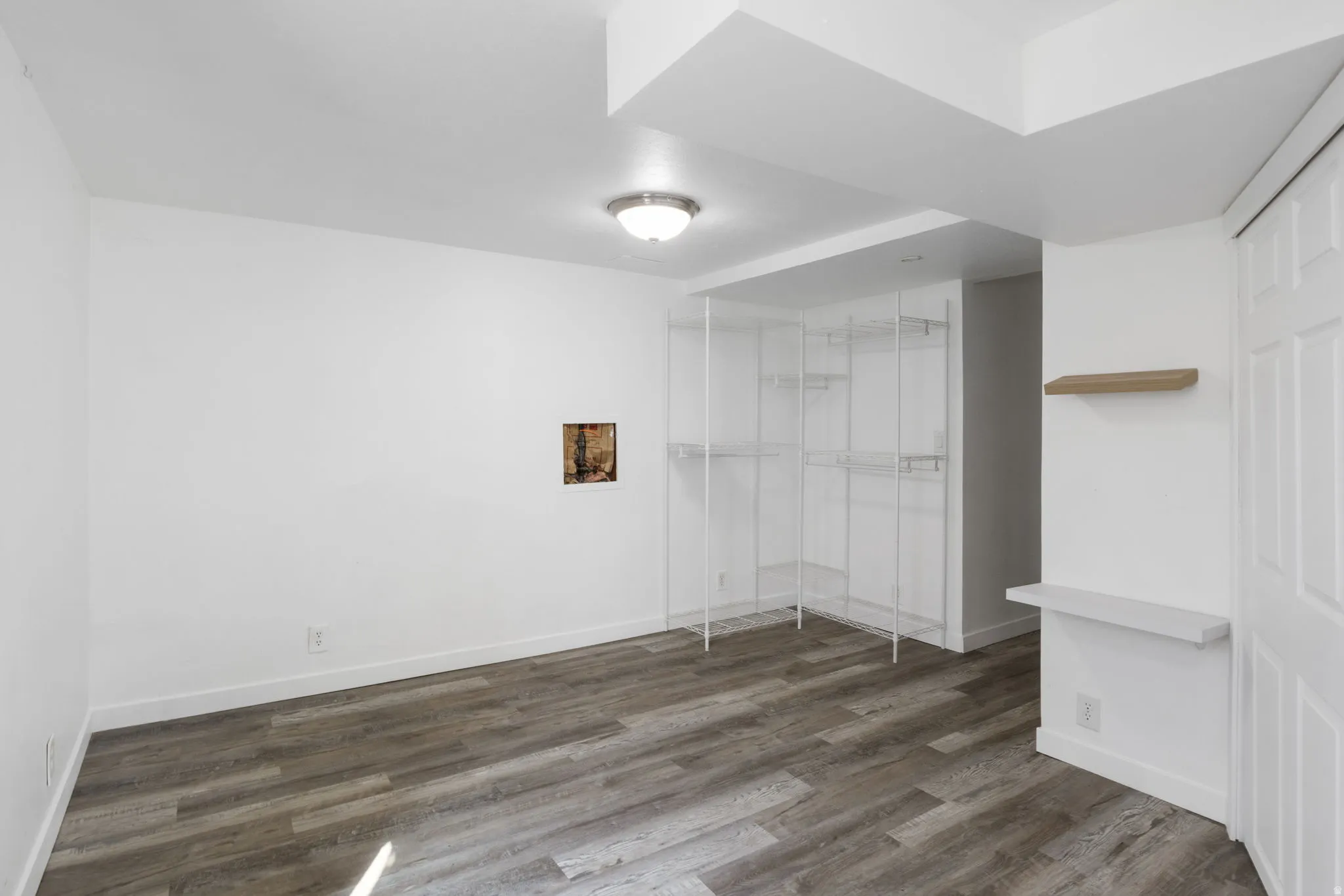 Bedroom 1 featuring dark vinyl floors additional storage and water shutoff