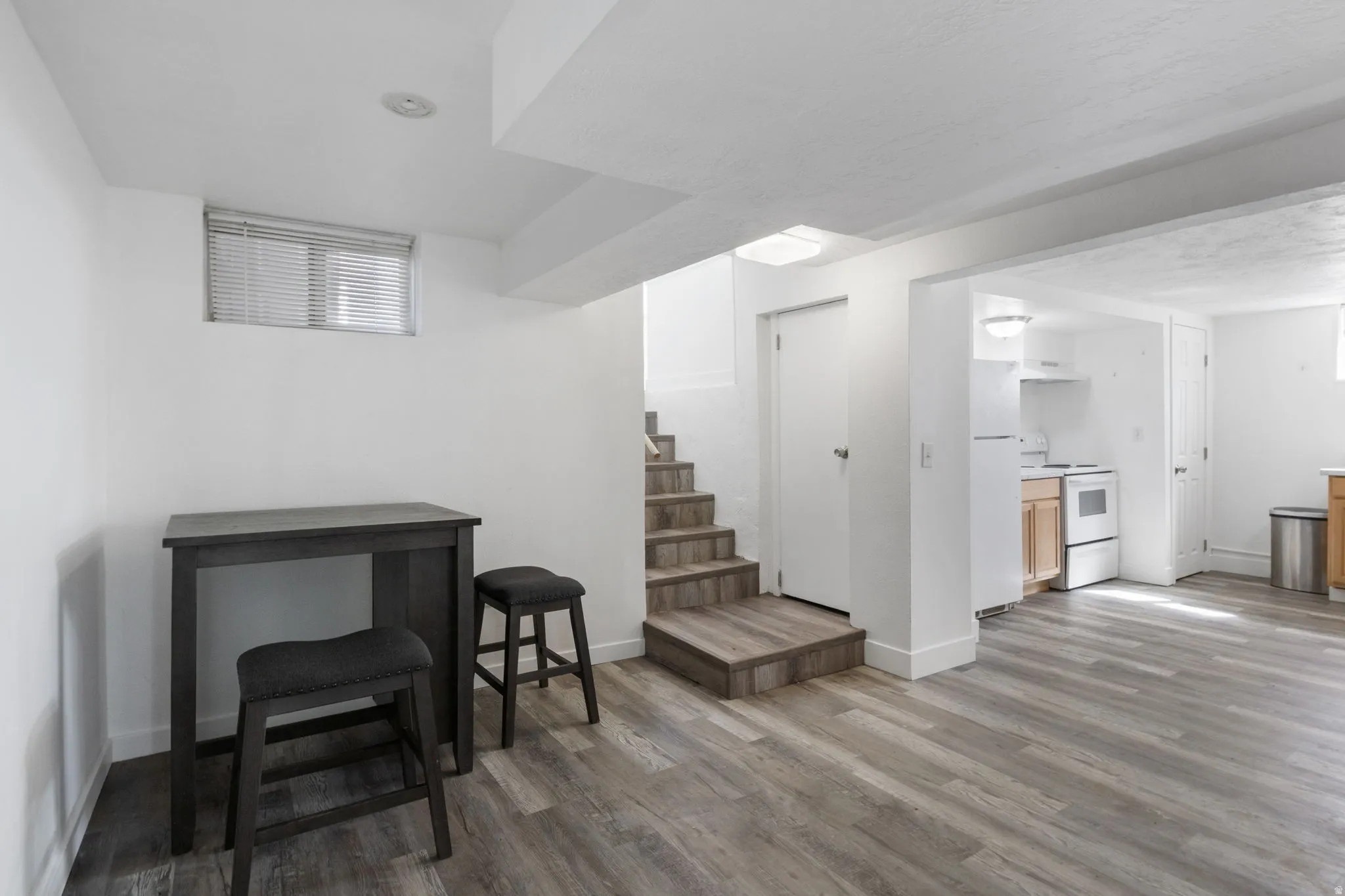 Finished basement featuring freestanding refrigerator and ligh vinyl flooring