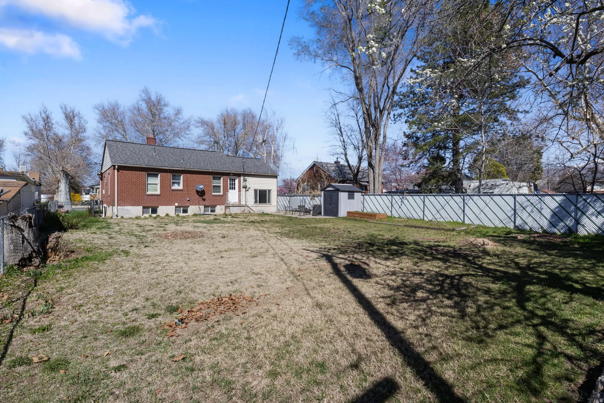 Back of house with a storage unit, a chimney, and a fenced backyard
