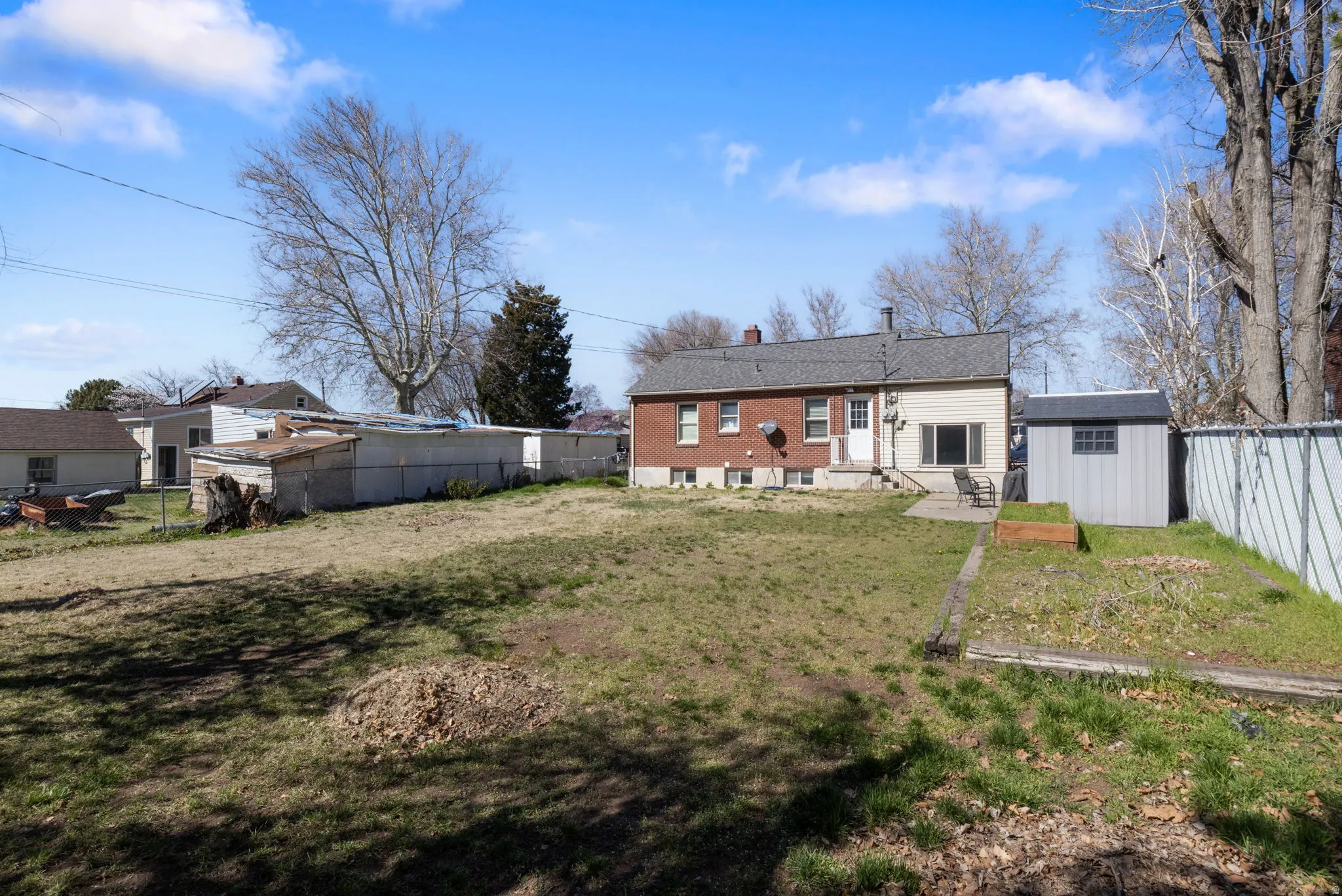 Back of house with a fenced backyard, a storage unit, and a chimney