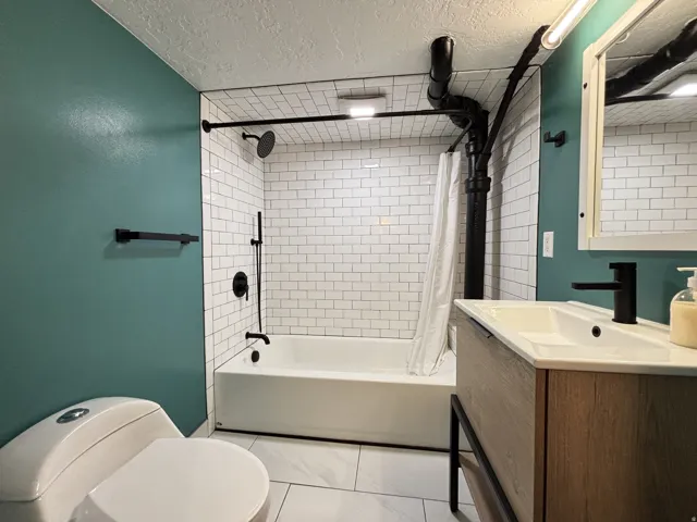 Bathroom with vanity, a textured ceiling, and shower / bath combo with shower curtain