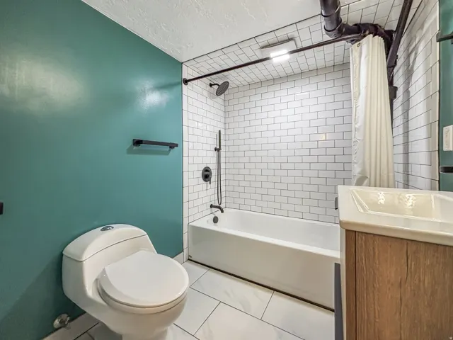 Bathroom featuring a textured ceiling, vanity, shower / tub combo, and light tile patterned flooring