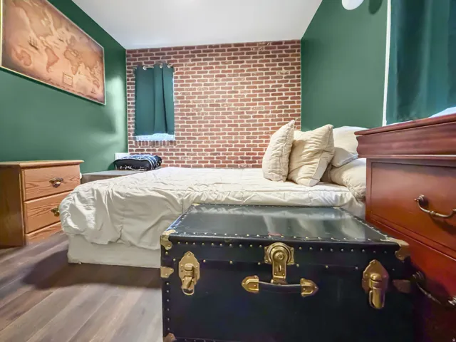 Bedroom featuring brick wall, an accent wall, and wood finished floors