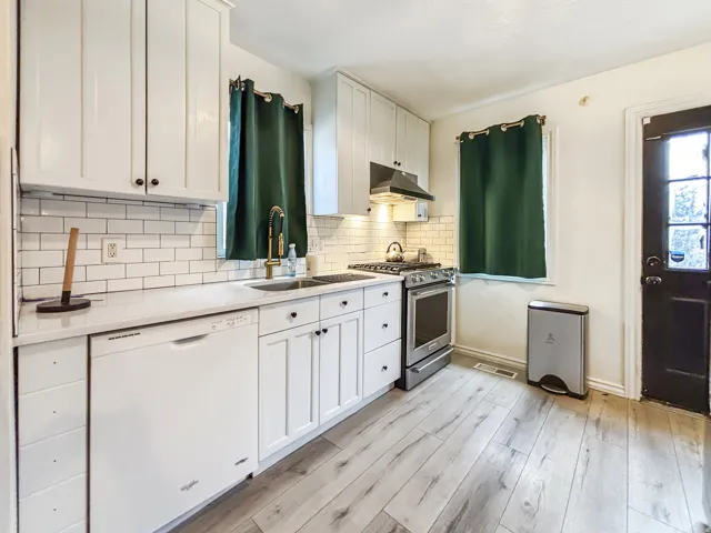 Kitchen featuring white cabinetry, white dishwasher, stainless steel range with gas cooktop, light wood-style flooring, and light stone countertops