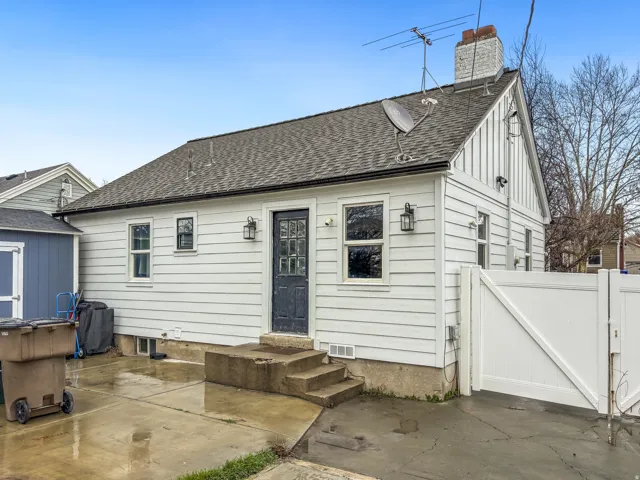 Rear view of property featuring a shingled roof, a chimney, a patio, and entry steps