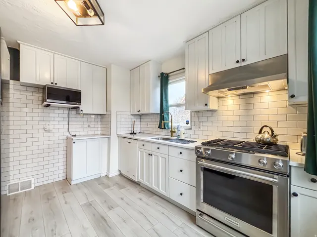 Kitchen with stainless steel range with gas cooktop, white cabinetry, light wood-style floors, dishwasher, and backsplash