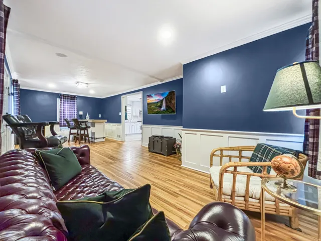 Living area featuring ornamental molding, a wainscoted wall, light wood finished floors, and a decorative wall