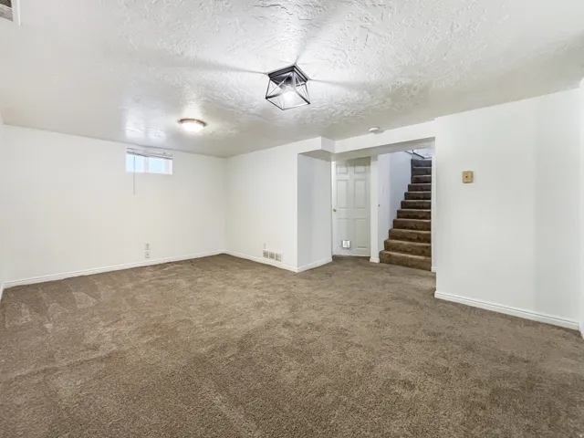 Below grade area with a textured ceiling and dark carpet